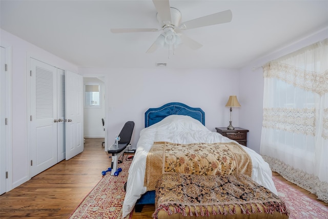 bedroom featuring multiple windows, hardwood / wood-style flooring, and ceiling fan