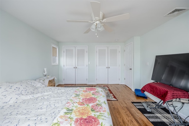 bedroom with ceiling fan, two closets, and light wood-type flooring