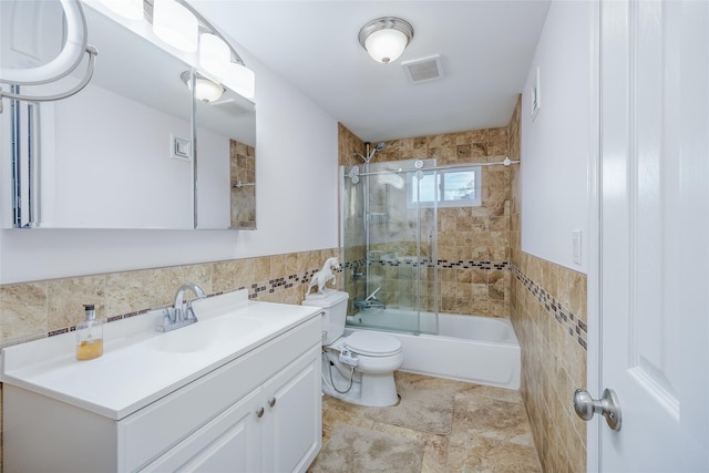 full bathroom featuring tile walls, vanity, bath / shower combo with glass door, and toilet