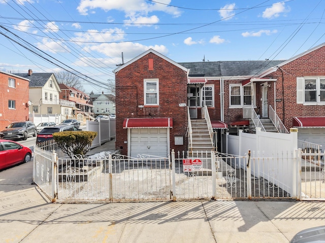 view of front of home with driveway, a fenced front yard, a garage, and brick siding