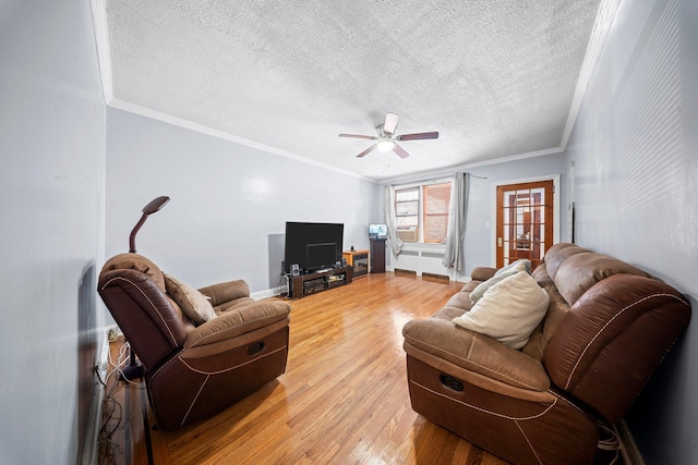 living room with ornamental molding, ceiling fan, a textured ceiling, wood finished floors, and baseboards