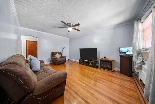 living room with baseboards, a textured ceiling, ornamental molding, and wood finished floors