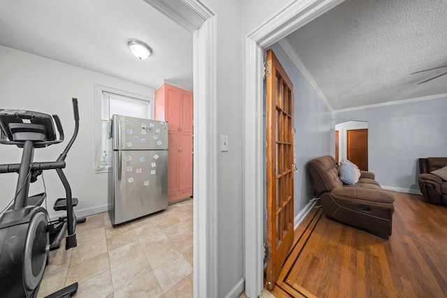 kitchen with baseboards, ornamental molding, open floor plan, freestanding refrigerator, and a textured ceiling