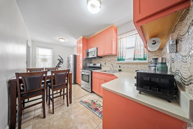 kitchen featuring light tile patterned flooring, stainless steel appliances, a sink, light countertops, and decorative backsplash