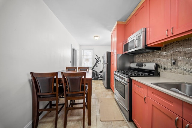 kitchen with tasteful backsplash, baseboards, stainless steel appliances, and light countertops