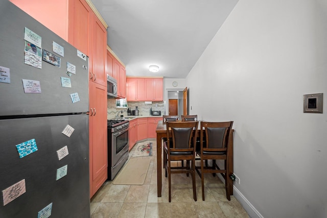 kitchen featuring light tile patterned floors, stainless steel appliances, tasteful backsplash, light countertops, and baseboards