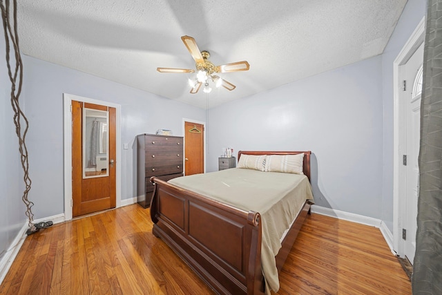 bedroom with a textured ceiling, wood finished floors, a ceiling fan, and baseboards