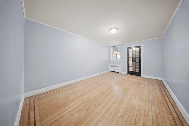 unfurnished room featuring ornamental molding, light wood-type flooring, radiator, and baseboards