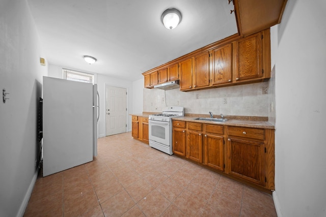 kitchen featuring white appliances, light countertops, a sink, and brown cabinetry