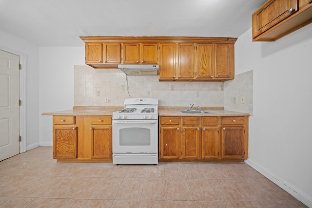 kitchen featuring under cabinet range hood, white range with gas cooktop, light countertops, and a sink