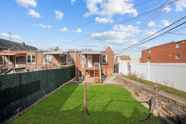 rear view of house featuring a fenced backyard, brick siding, and a lawn