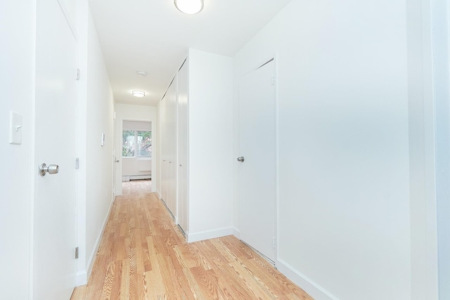 hall with a baseboard heating unit and light hardwood / wood-style floors