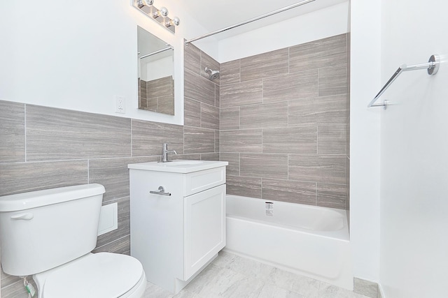 full bathroom featuring vanity, tiled shower / bath, tile walls, and toilet