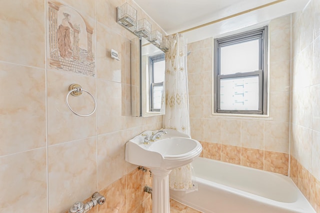 bathroom with shower / tub combo with curtain and tile walls