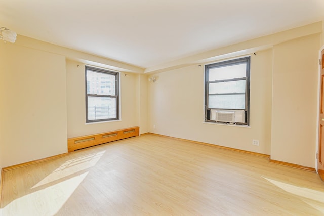 empty room featuring baseboard heating and hardwood / wood-style flooring