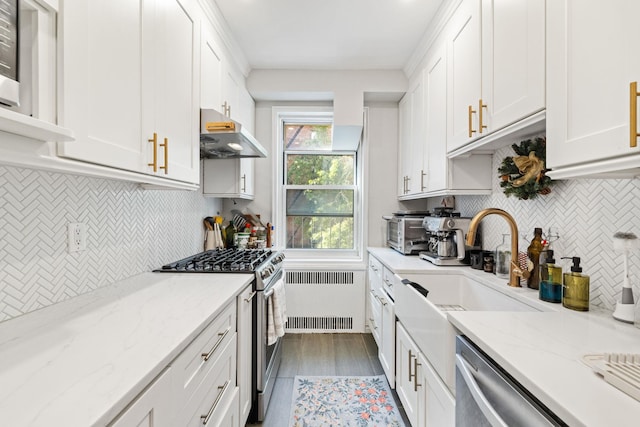 kitchen featuring radiator heating unit, light stone countertops, white cabinets, and appliances with stainless steel finishes