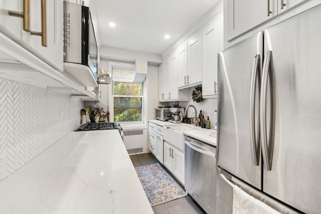 kitchen featuring white cabinetry, radiator heating unit, light stone countertops, and appliances with stainless steel finishes