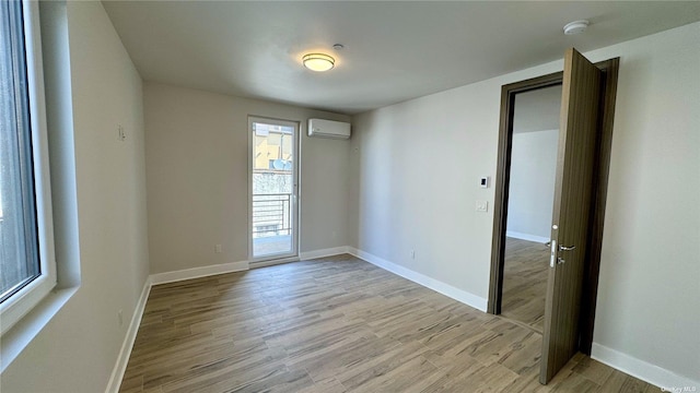 spare room featuring a wall mounted AC and light hardwood / wood-style flooring