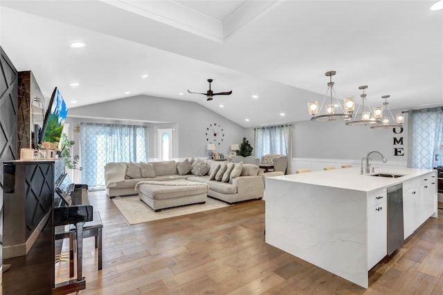 kitchen featuring sink, light hardwood / wood-style flooring, white cabinetry, an island with sink, and decorative light fixtures