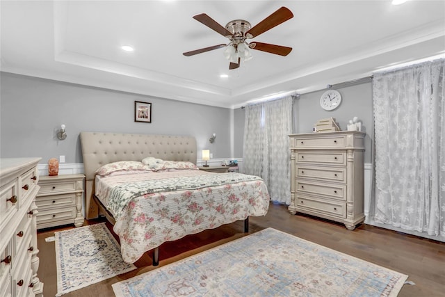 bedroom with a raised ceiling, dark wood-type flooring, and ceiling fan