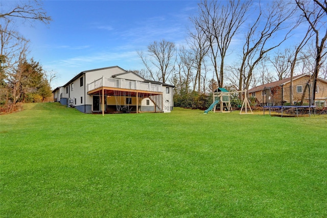 view of yard featuring a trampoline, a playground, and a deck