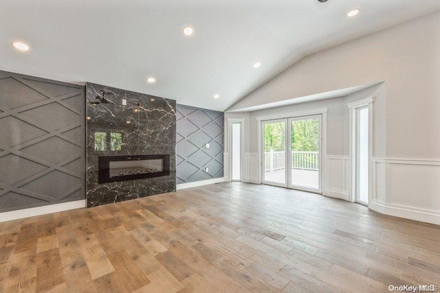 unfurnished living room featuring vaulted ceiling, a fireplace, and light hardwood / wood-style floors