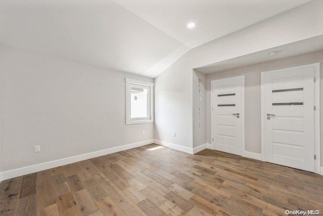 unfurnished room with hardwood / wood-style flooring and vaulted ceiling