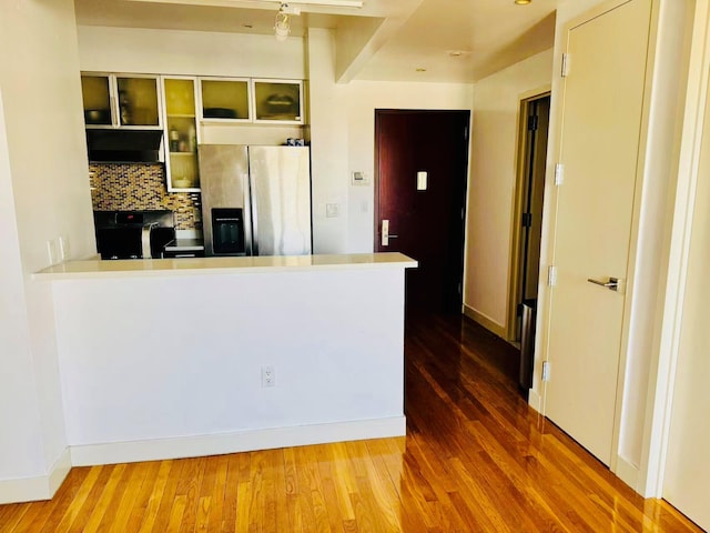 kitchen with hardwood / wood-style floors, decorative backsplash, stainless steel fridge, and kitchen peninsula