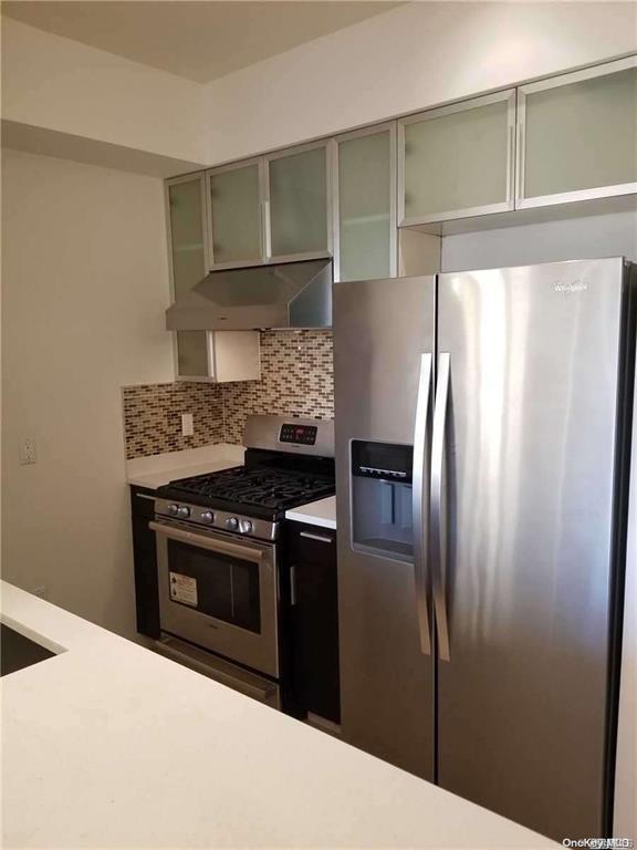 kitchen with stainless steel appliances, green cabinetry, and decorative backsplash