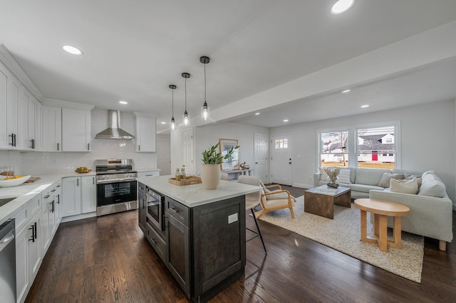 kitchen with a kitchen island, white cabinets, a kitchen breakfast bar, stainless steel appliances, and wall chimney range hood