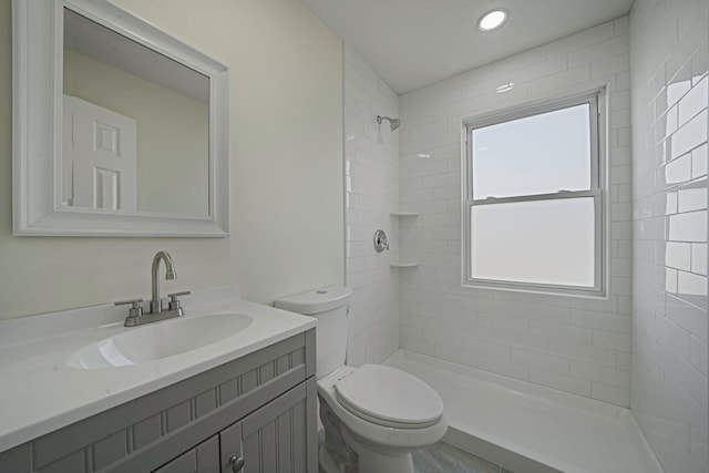 bathroom featuring vanity, toilet, and a tile shower