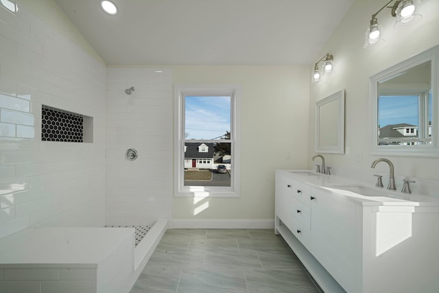 bathroom featuring vanity, vaulted ceiling, and tiled shower