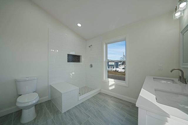 bathroom with tiled shower, lofted ceiling, toilet, and vanity