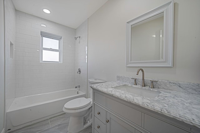 full bathroom featuring tiled shower / bath combo, vanity, and toilet