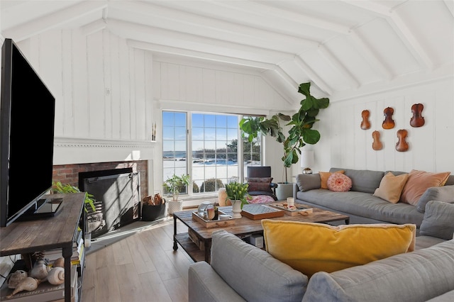 living room with a water view, a fireplace, lofted ceiling with beams, and hardwood / wood-style flooring