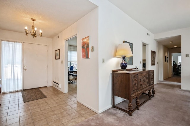 foyer entrance featuring light colored carpet, visible vents, baseboard heating, an inviting chandelier, and baseboards