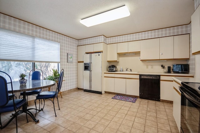 kitchen featuring light countertops, a sink, a textured ceiling, black appliances, and wallpapered walls