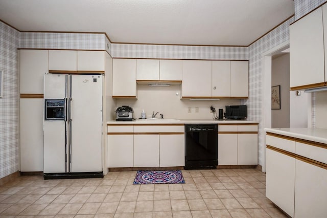 kitchen featuring light countertops, white cabinets, white fridge with ice dispenser, dishwasher, and wallpapered walls