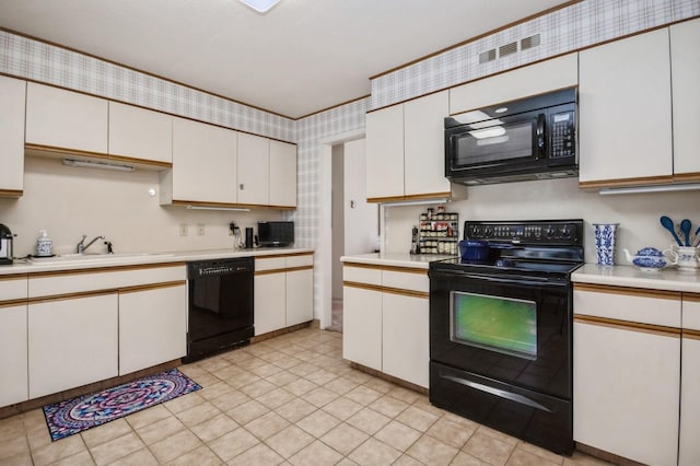 kitchen with a sink, black appliances, white cabinets, and light countertops