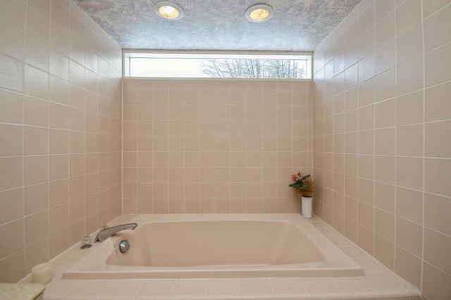 full bath with a textured ceiling and a tub to relax in