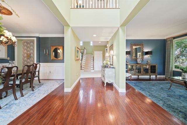 foyer entrance featuring a chandelier, wood finished floors, stairs, and crown molding