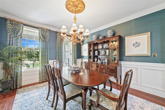 dining room with a chandelier, a wainscoted wall, crown molding, and wood finished floors