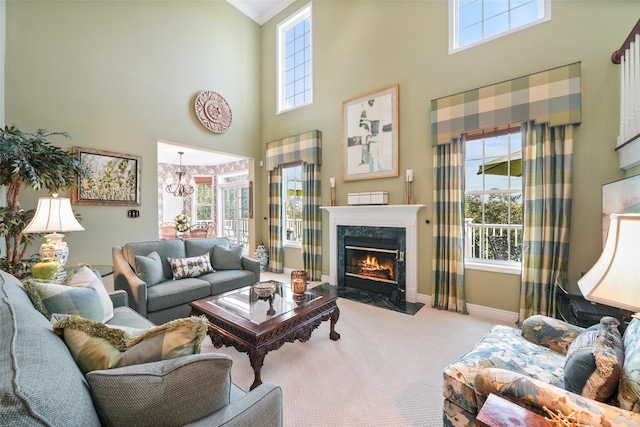 living room with a notable chandelier, a high ceiling, a high end fireplace, light carpet, and baseboards