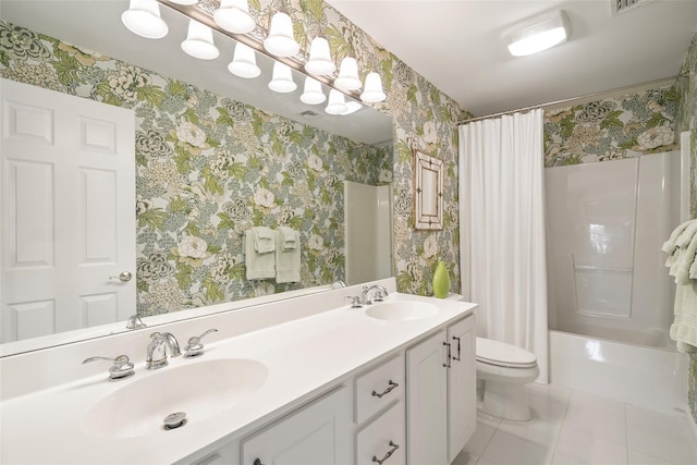 bathroom featuring double vanity, a sink, toilet, and wallpapered walls