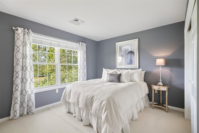 bedroom featuring baseboards, visible vents, and light colored carpet