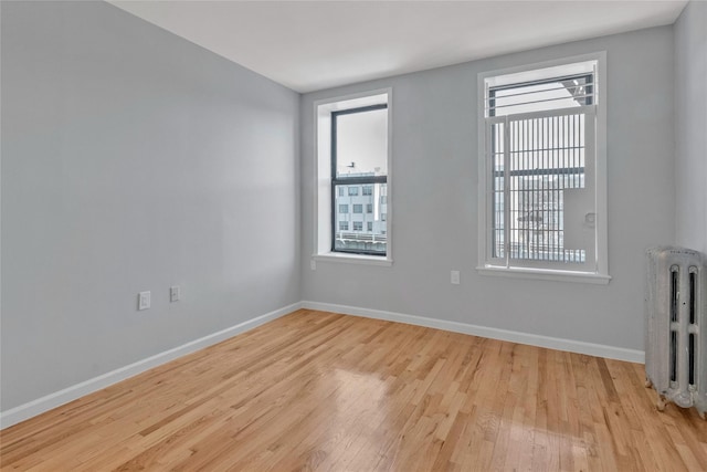 spare room featuring radiator heating unit and light wood-type flooring