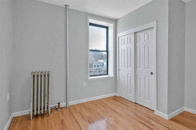 unfurnished bedroom featuring radiator, a closet, and light wood-type flooring