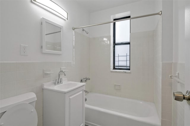 full bathroom featuring vanity, toilet, tiled shower / bath combo, and tile walls