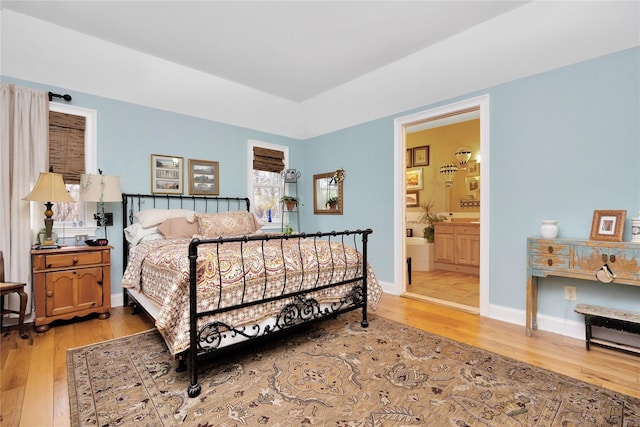 bedroom featuring ensuite bath and light wood-type flooring