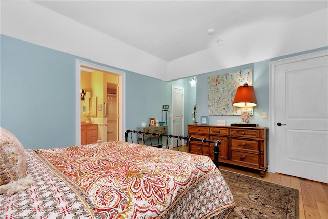 bedroom with ensuite bathroom and hardwood / wood-style floors